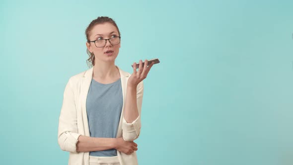 Woman with Glasses Smiles and Talks the Phone on a Loudspeaker in the Studio alt