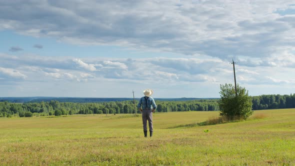 Farmer Standing in Mown Field Looking Far Ahead alt