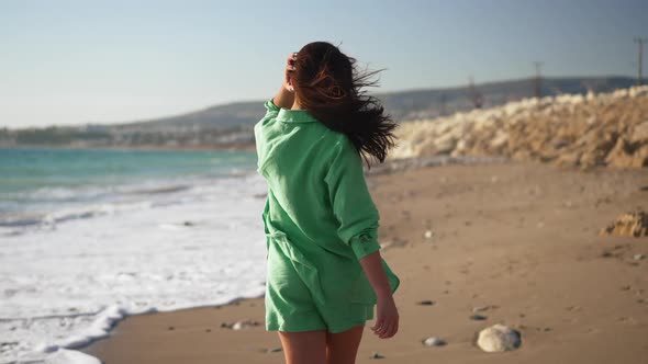Back View of Slim Cheerful Young Brunette Woman Walking in Slow Motion on Sandy Sunny Beach Turning alt