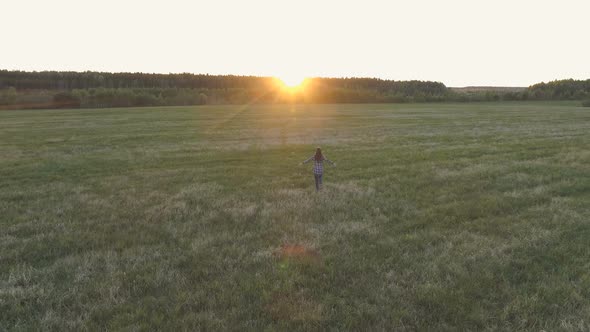 Unrecognizable Woman Walking on the Field at Sunset Arms Outstretched