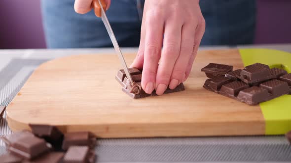 Woman Chopping Black Dark Chocolate on Wooden Cutting Board alt