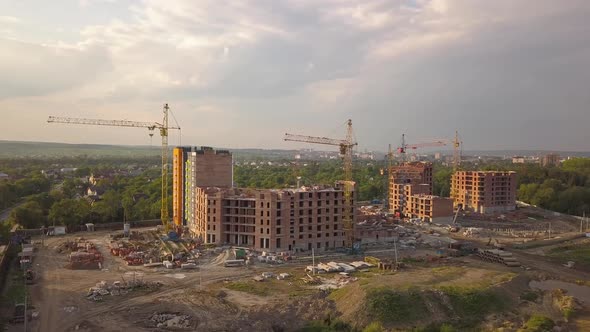 Aerial view of construction site with building cranes and high rise apartment buildings in a city. alt