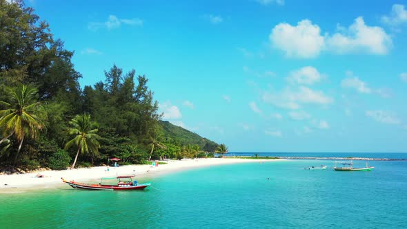 Tropical beach background. Sandy beach calm lagoon with fishing boats bright blue sky. alt