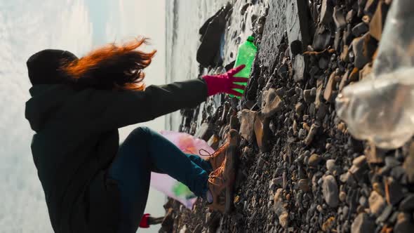 A female volunteer put a plastic dirty bottles in a garbage bag.Vertical orientation alt