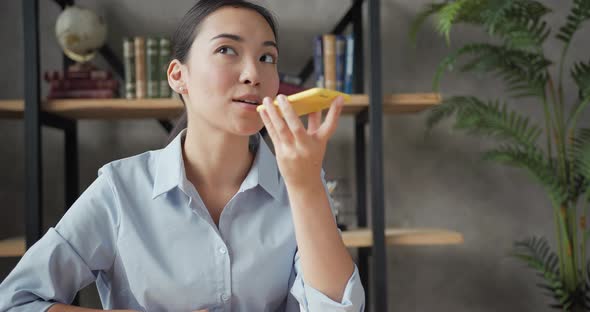 Close Up Portrait of Smiling Asian Business Woman Recording a Voice Message to Someone Using alt