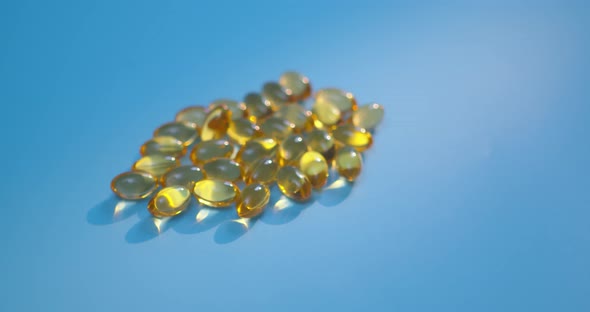 Omega 3 Gold Fish Oil Capsules Rotation on Blue Background