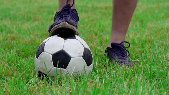 Man's Foot in a Sneaker Swings a Ball Before Hitting It on Green Grass Close Up alt