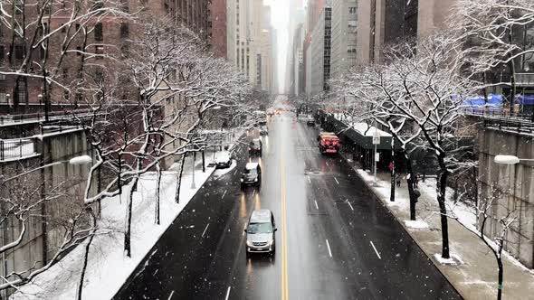 Tilt Up Shot of Snow Falling Over Buildings and Street in Midtown alt