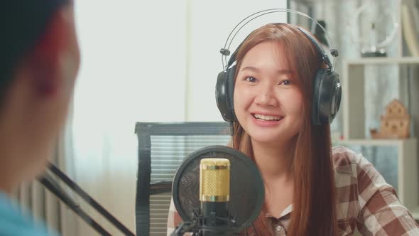 Over Shoulder View Of Asian Man Host Record Podcast Interview Happy Female Guest In Home Studio alt