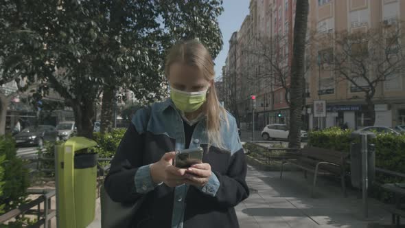 Woman in Mask Walking in the Street Being Attracted to Mobile
