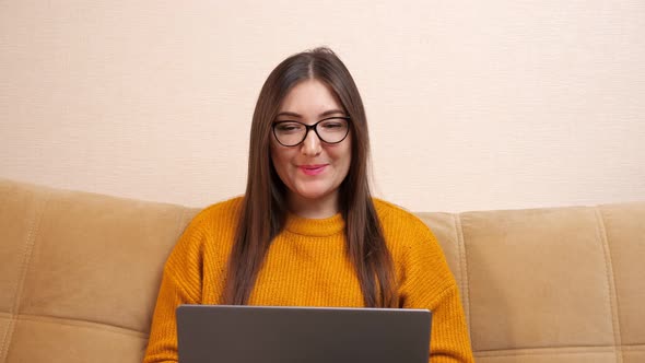 Young Woman Looks on Grey Laptop Display Sitting at Home alt