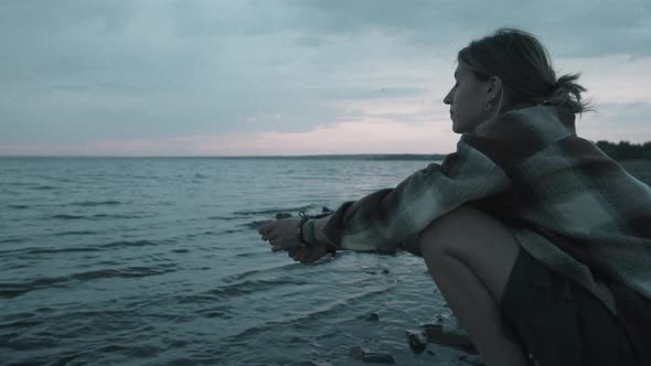 Woman Throwing Pebbles into Lake alt