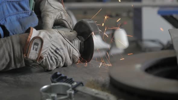 A Worker Works With A Grinder. Hands Of Workman Cutting Metal Detail With Grinder