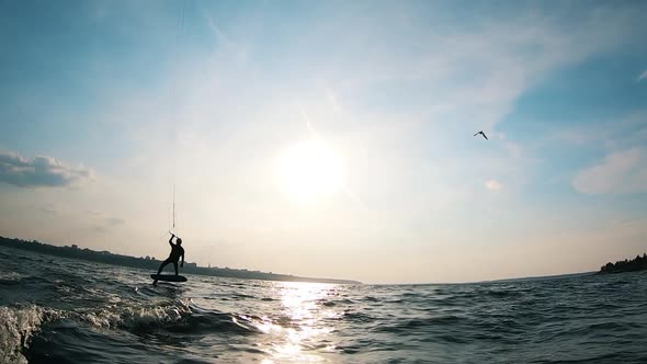 A Man Is Kitesurfing Along the Riverbank alt