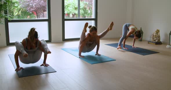 Sportswomen improving concentration while doing Tittibhasana yoga pose alt
