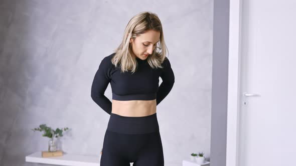 Young Slim Woman in Sportswear Measuring her Waist with Tape at Home, Copy Space alt