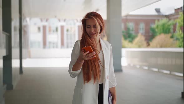 Pretty Successful business woman using mobile phone texting on urban street. alt