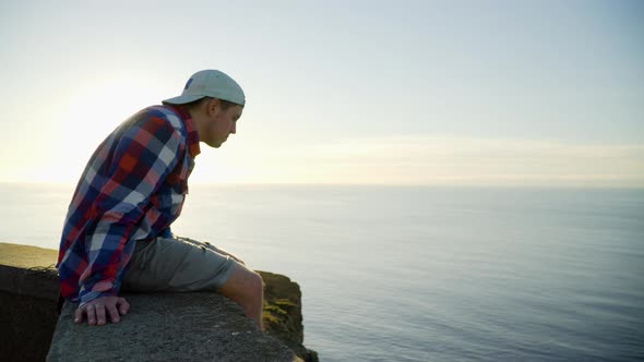 Young man looking at sunset view, ocean and sunlight in the background alt