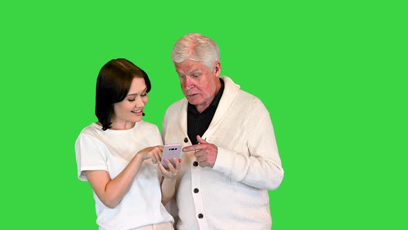 Daughter Shows Pictures on a Mobile Phone To Her Old Father on a Green Screen Chroma Key alt