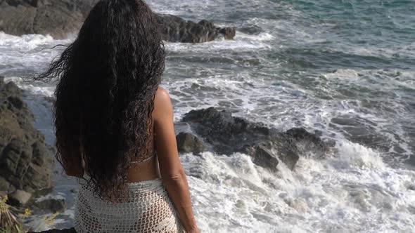 Woman looking out over coast of Costa Rica with crashing ocean waves alt
