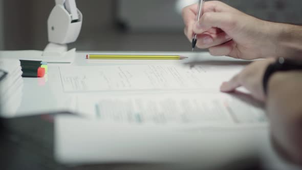Student Writing Down Important Notes On A Sheet Of Bond Paper Atop On Study Table. - close up shot alt