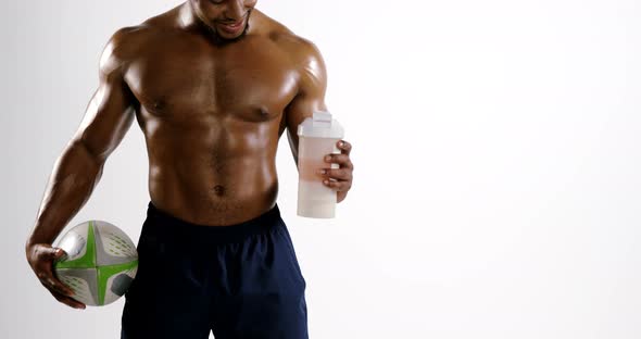 American football player holding a water bottle and rugby ball alt
