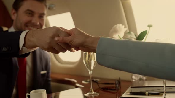 Business People Shaking Hands on Private Jet Closeup alt