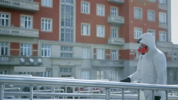 Man Disinfecter Spray Handrail City Street. Corona Virus. Covid-19. Coronavirus. alt