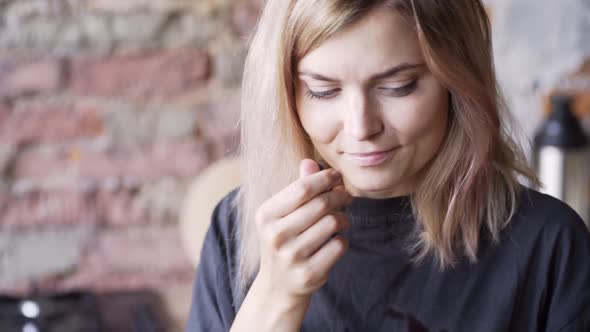 Blonde with Loose Flowing Hair Holds Green Basil Leaves