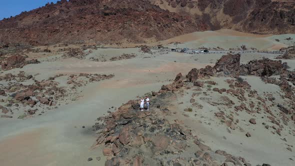 Tenerife, Lunar Landscape in the Crater of the Teide Volcano. Woman and a Man in White Clothes Stand alt