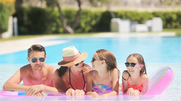 Happy Family of Four in Outdoors Swimming Pool alt