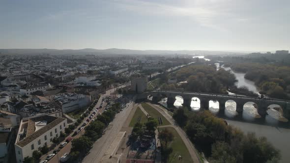 Orbiting over Guadalquivir river with Calahorra Tower on Famous Roman Bridge, Cordoba. Spain