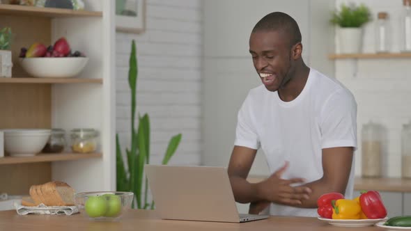 Sporty African Man Doing Video Call on Laptop in Kitchen alt