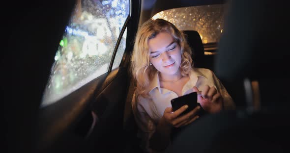 Woman Sitting in the Car and Flipping Through the Phone