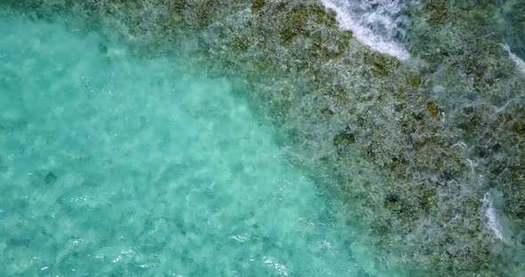 Sea waves passing over coral reefs and rocky seabed, foaming over turquoise lagoon with calm clear w alt