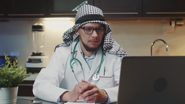 Close Up Shot of Arabic Doctor with Kandora Making Video Call on Computer From Home