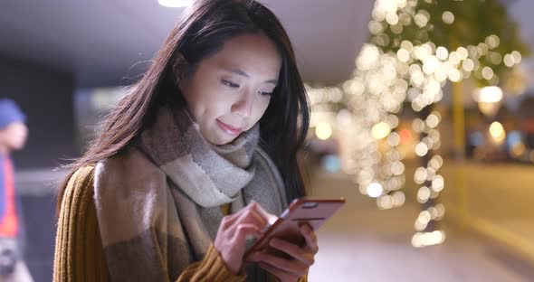 Woman working on cellphone in the city at night alt
