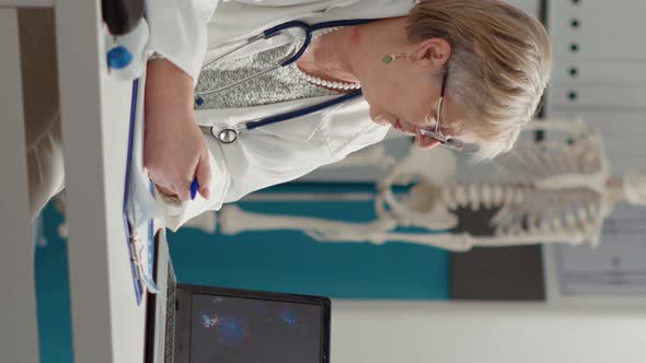 Vertical Video Female Medic Looking at Coronavirus Illustration on Laptop alt