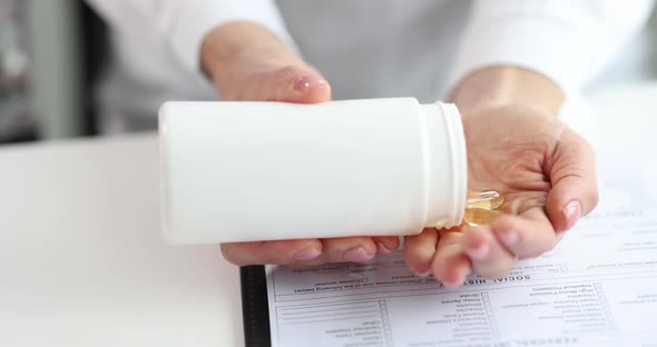 Doctor or Patient Pours Omega 3 Vitamins Pill From Jar alt
