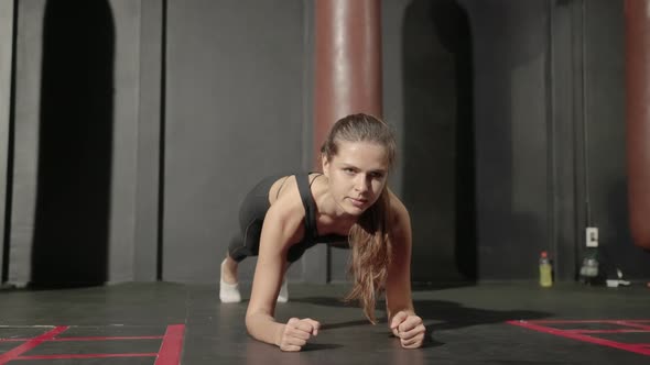 sports girl doing plank pose to work out the mid-body strength in the gym