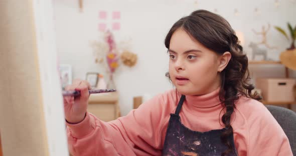 Front View of Beautiful Young Lady Smiling While Painting Picture in Room. Sympathetic Teenager Girl alt