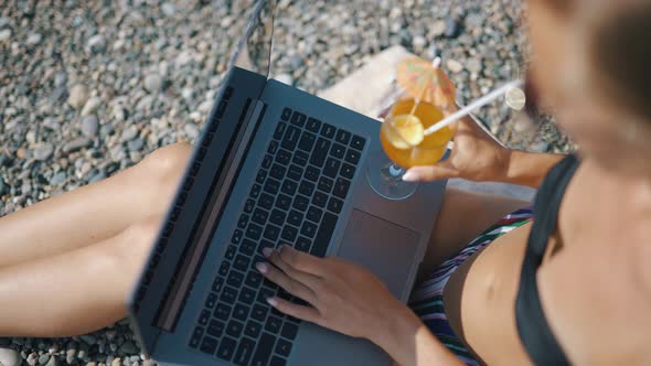 A Female Freelancer is Working on Laptop Near Sea alt