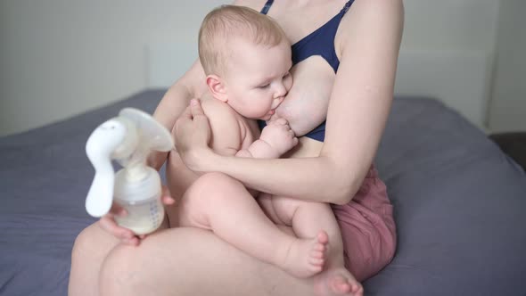 Young Mother with Newborn Cute Infant Naked Baby Boy Holding Him on Arms Using Breast Pump Hugging