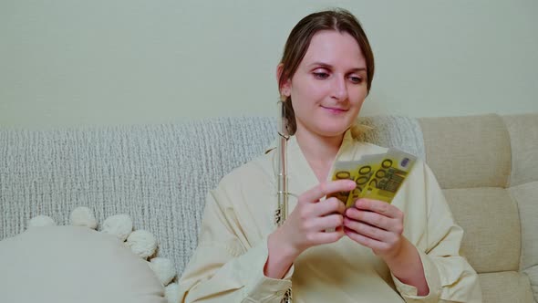 Woman musician with money in euro at home on sofa in living room