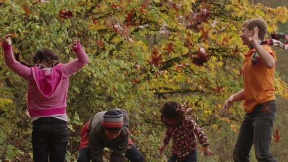 Group of kids in Fall throwing leaves