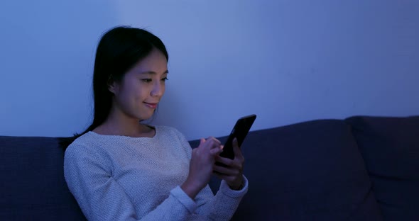 Woman use of mobile phone at home in the evening alt