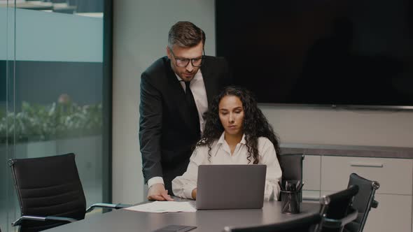 Female And Male Colleagues Working Together Using Laptop In Office alt