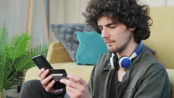 Young Man Shopping Online with Credit Card Using Smart Phone at Home alt