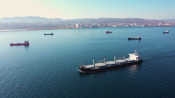 Aerial View Following the Ultra Large Cargo Ship at Sea Leaves Port at Sunset alt