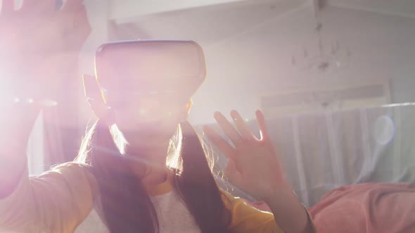 Happy asian girl at home, sitting on floor in living room enjoying using vr headset, backlit alt